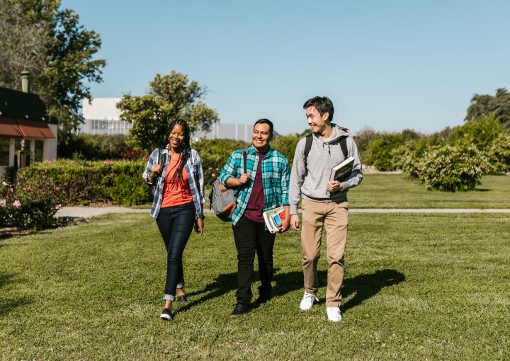 College Students Walking on Grass Field